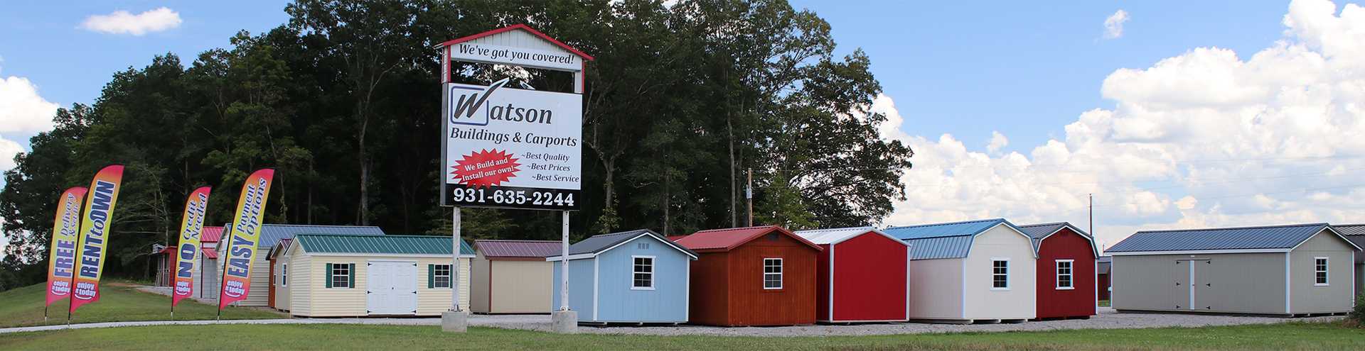 Row of barns with a sign in front against a blue sky