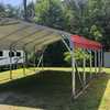 Rounded frame carport with red roof on green grass